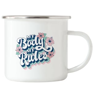 Pode incluir: Caneca de esmalte branca com aro e alça prateados. A caneca apresenta o texto "MY Body MY Rules" em uma fonte retrô, rodeado por flores rosa e azuis e folhas verdes.