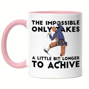 Puede incluir: Taza de cerámica blanca con borde y asa de color rosa. La taza presenta una ilustración en blanco y negro de un escalador y el texto "Lo imposible solo tarda un poco más en lograrse."