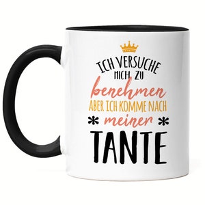 Könnte beinhalten: Weiße Keramiktasse mit schwarzem Rand und Henkel. Die Tasse zeigt eine schwarze und goldene Krone, schwarzer Text, der "Ich versuche mich zu benehmen aber ich komme nach *meinen* TANTE" in einer verspielten Schriftart lautet.