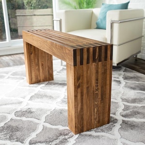 May include: A rustic wooden console table with a slatted top and a natural brown finish. The table has a rectangular shape and is supported by four legs.