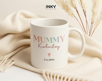 Puede incluir: Taza de cerámica blanca con un diseño de "Mummy" colorido y el nombre "Kimberly" en escritura rosa. La taza también tiene un pequeño corazón y el texto "Est. 2024".