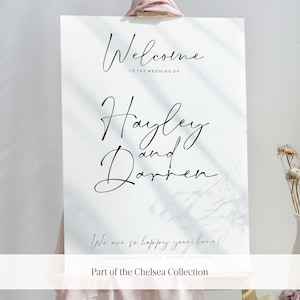 May include: A white welcome sign with black calligraphy text that reads "Welcome to the wedding of Hayley and Darren." The sign also includes the date "05th September 2023" and the location "Grand Junction". The sign is part of the Chelsea Collection.
