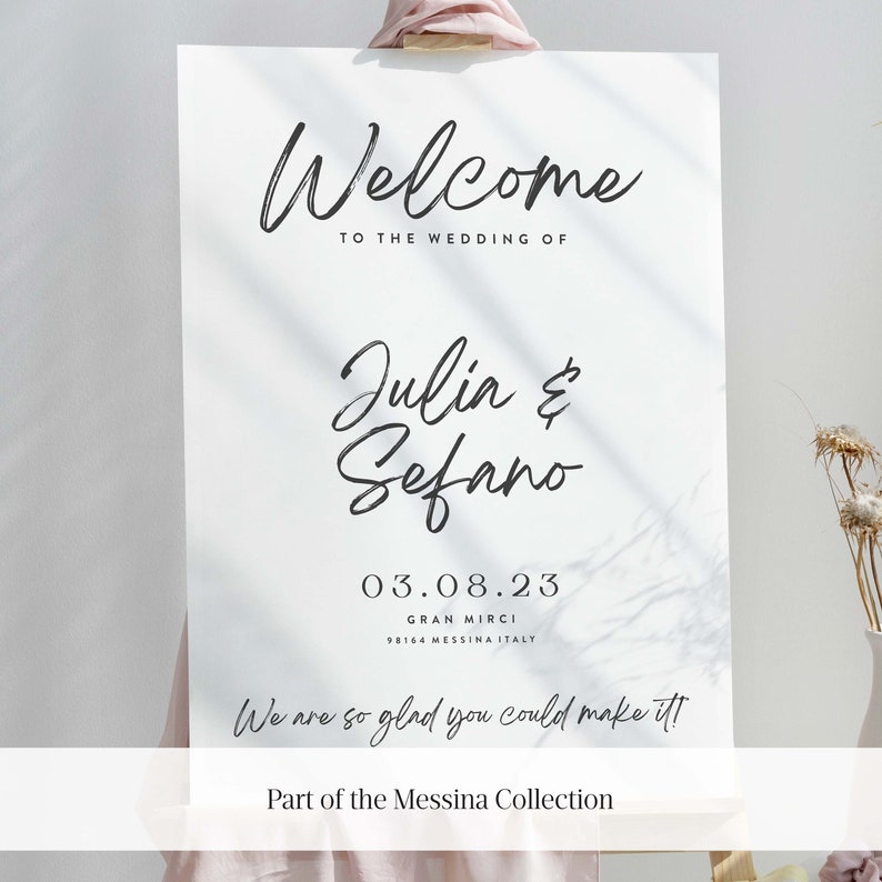 May include: White wedding welcome sign with black calligraphy text that reads "Welcome to the wedding of Julia & Sefano 03.08.23 Gran Mirci 98164 Messina Italy We are so glad you could make it! Part of the Messina Collection"