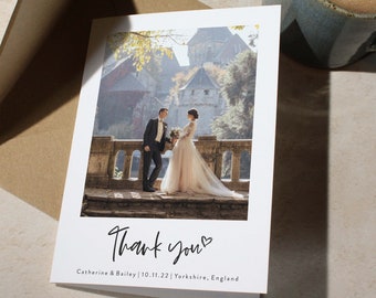 May include: A wedding thank you card with a photo of a bride and groom in front of a castle. The card says "Thank you" with a heart and "Catherine & Bailey | 10.11.22 | Yorkshire, England".