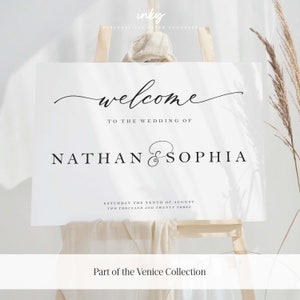 May include: White wedding welcome sign with black calligraphy text that reads "Welcome to the wedding of Nathan & Sophia" and "Saturday the tenth of August, Two thousand and twenty three". The sign is on a wooden easel and has the text "Part of the Venice Collection" at the bottom.