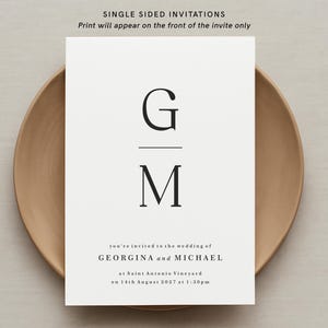 May include: A minimalist wedding invitation with the initials "G" and "M" in a black serif font. The text reads "you're invited to the wedding of GEORGINA and MICHAEL at Saint Antonio Vineyard on 14th August 2027 at 1:30pm."