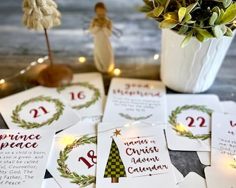May include: A set of Christmas advent calendar cards with green wreaths and red numbers. The cards feature quotes about the birth of Jesus Christ, including the names of Christ, Messiah, Savior, and Prince of Peace.