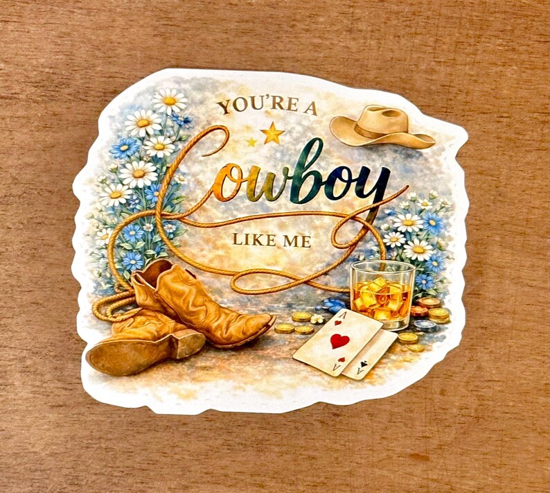 May include: A sticker with a cowboy theme. It features a cowboy hat, boots, a glass of whiskey, playing cards, and the text "You're a Cowboy Like Me" surrounded by flowers and a rope.