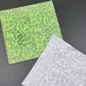May include: Two sheets of patterned paper, one green and one silver, with a floral and bird design. The green sheet has a white outline and the silver sheet has a black outline.
