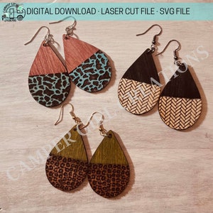 May include: Three pairs of wooden teardrop-shaped earrings. The earrings are split in half, with the top half a solid color and the bottom half a patterned design. The colors are brown, black, green, teal, and beige.