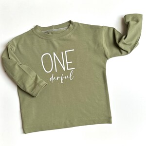 Könnte beinhalten: Ein hellgrünes Langarmshirt mit dem Text "ONEderful" in Weiß.