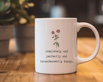May include: White ceramic mug with a floral design and the text "completely and perfectly and incandescently happy."