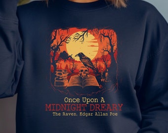 May include: A navy blue sweatshirt with a graphic print of a raven perched on a book with a skull. The graphic is set against a backdrop of a full moon and a spooky forest. The text "Once Upon A MIDNIGHT DREARY The Raven, Edgar Allan Poe" is printed below the graphic.