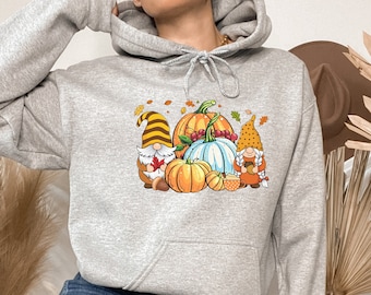 May include: A gray hoodie with a graphic of two gnomes holding pumpkins and gourds. The gnomes are wearing red and white hats and have white beards. The pumpkins are orange and the gourds are green.