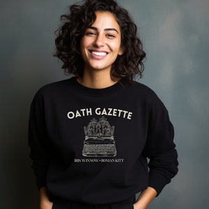 Puede incluir: Sudadera negra con un gr&aacute;fico blanco de una m&aacute;quina de escribir con flores y el texto "OATH GAZETTE IRIS WINNOW - ROMAN KITT"