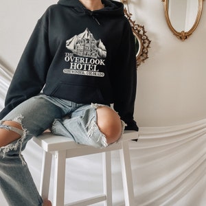 May include: Black hoodie with a white graphic of a mountain and building with the text "The Overlook Hotel, Sidewinder, Colorado".