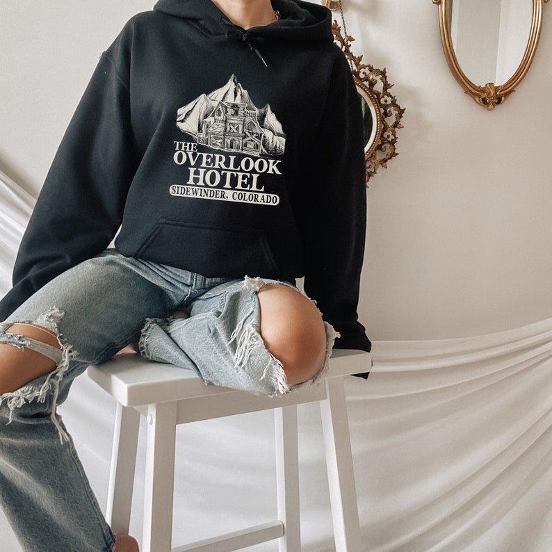 May include: Black hoodie with a white graphic of a mountain and building with the text "The Overlook Hotel, Sidewinder, Colorado".