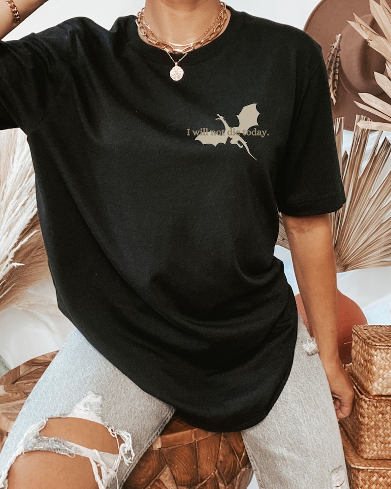 May include: Black oversized t-shirt with a silhouette of a dragon and the text "I will not die today."