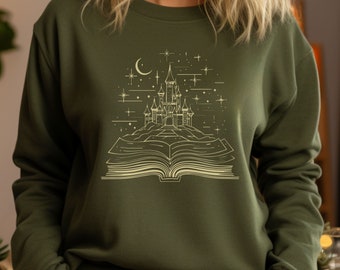 May include: A green sweatshirt featuring a gold outline of a castle on a book with stars and a crescent moon.