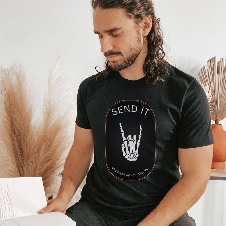 May include: Black t-shirt with a white skeleton hand making a rock and roll sign in a red oval with the text "SEND IT" and "NO VICTORY WITHOUT SACRIFICE" in white.