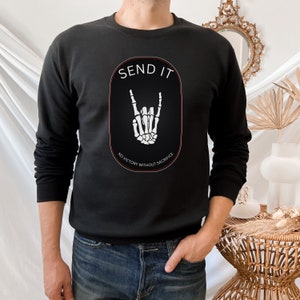 May include: Black sweatshirt with a white graphic of a skeleton hand making the rock and roll sign. The graphic is inside a circle with the text "SEND IT" above the hand and "NO VICTORY WITHOUT SACRIFICE" below the hand.