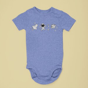 May include: A light blue baby onesie with a white astronaut, rocket, and planet design.