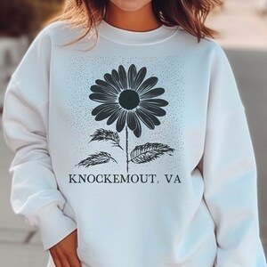 Puede incluir: Sudadera blanca con un gr&aacute;fico en blanco y negro de una margarita con el texto "Knockemout, VA" impreso en la parte delantera.