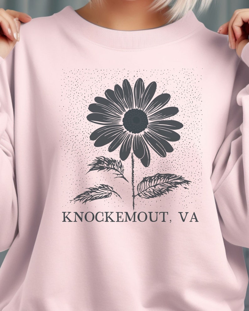 Puede incluir: Una sudadera rosa con un gr&aacute;fico en blanco y negro de una flor y el texto "Knockemout, VA".