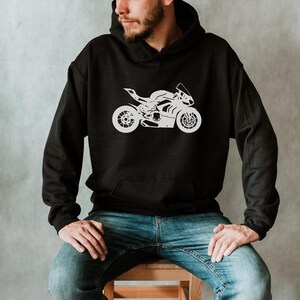 Op de afbeelding: Een zwarte hoodie met een wit silhouet van een motorfiets op de voorkant. De hoodie heeft een capuchon met trekkoord en een kangoeroezak.