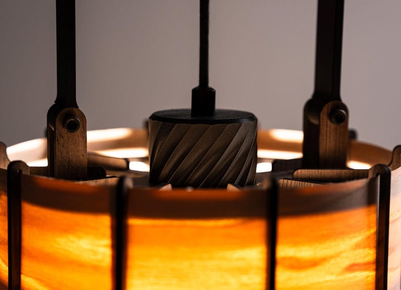 Pu&ograve; includere: Primo piano di un lampadario in legno. Il lampadario ha un centro cilindrico con un design intagliato, sostenuto da bracci in legno e un paralume caldo e luminoso. Il design incorpora toni di legno naturale e una luce calda.
