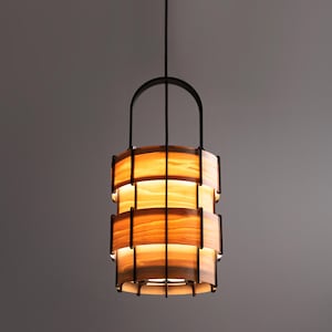 May include: A modern pendant light fixture with a black metal frame and a warm wood shade. The shade is made of multiple layers of wood, creating a unique and stylish design.