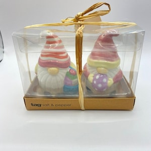 May include: A set of two ceramic gnome salt and pepper shakers in a clear plastic box, tied with raffia. The gnomes have white beards, colorful hats, and hold Easter eggs. The box is labeled "tag salt & pepper".