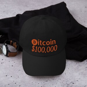 May include: Black baseball cap with an orange embroidered Bitcoin logo and the text "$100,000".