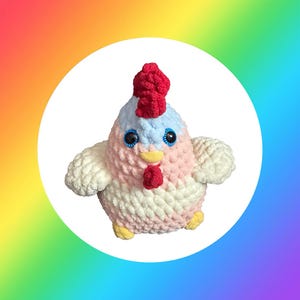 May include: A soft, handmade chicken toy in pastel shades. The chicken has a red comb and wattle, blue eyes, and a yellow beak. The body is made from pink, white, and blue yarn. The toy is designed to be soft and cuddly.