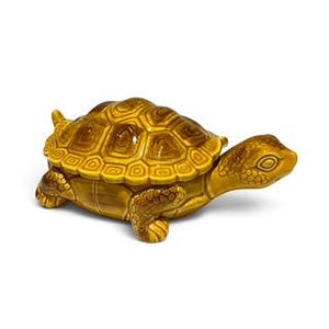 May include: A ceramic turtle-shaped trinket box with a glossy finish in shades of golden yellow and brown. The shell features a raised, geometric pattern of hexagonal plates, while the head and legs show detailed, textured skin markings.