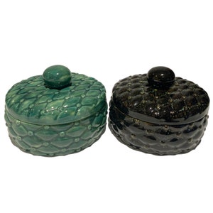 May include: Two ceramic lidded boxes with a quilted design. One box is green and the other is black.