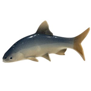 May include: A ceramic fish figurine with a blue-grey body, tan fins, and a tan tail. The fish has a sleek, streamlined design, and is likely a decorative item. The figurine is set against a white background.