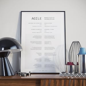 Könnte beinhalten: Ein schwarz-weißes Poster mit dem Text "Agile Manifesto Principles" und einer Liste von Prinzipien für agile Softwareentwicklung. Das Poster ist gerahmt und hängt an einer Wand.
