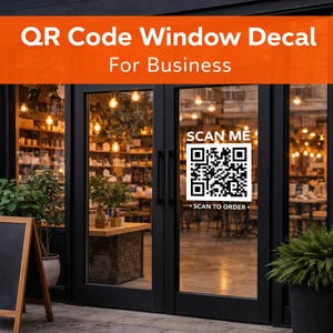 May include: A shop entrance featuring a QR code window decal. The decal says "Scan Me" and "Scan to Order." The black door has an orange banner above it that reads "QR Code Window Decal For Business."