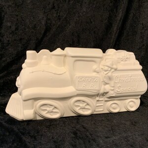 May include: White ceramic Christmas train with the words "Santa R.R. Christmas Special" on the side. The train has a figure of Santa Claus on the front.