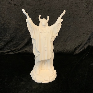 Peut inclure: Figurines en céramique blanche d'une personne avec des cornes, portant une longue robe et debout les bras levés. La figurine est sur une base rocheuse.