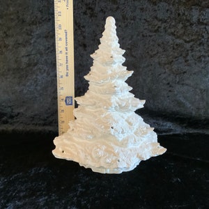 May include: White ceramic Christmas tree figurine with a textured surface. The tree is approximately 7 inches tall.