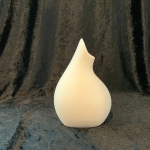 May include: A white ceramic vase with a unique, organic shape. The vase has a wide opening at the top and a narrow base.