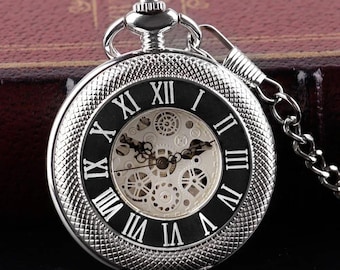 May include: A silver pocket watch with a black face and Roman numeral hour markers. The watch has a skeletonized movement, allowing the inner workings to be seen. The watch is on a chain.