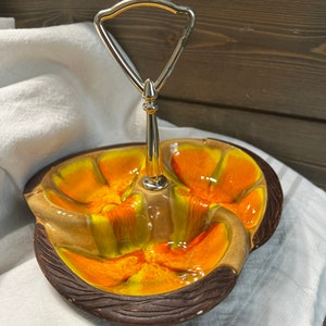 May include: A ceramic serving dish with a metal handle. The dish is divided into three sections and has a brown, orange, and yellow glaze.