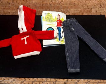 May include: Red hooded sweater with a white letter "T" on the front, blue denim jeans, and a vintage book with a girl wearing a red sweater and blue jeans.