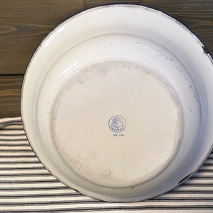 May include: White enamelware bowl with a blue rim and a blue and white logo on the bottom that reads "24 cm".