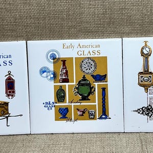 May include: Three square white ceramic tiles featuring illustrations and text. The first tile displays Early American BRASS items. The second tile shows Early American GLASS objects. The third tile depicts Early American CLOCKS with detailed drawings.