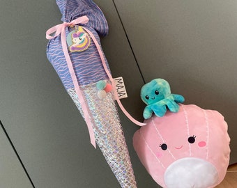 May include: A pink and purple mermaid-themed school cone with a unicorn charm and a pink and white plush octopus on top. The cone has a tag that says "MAJA".