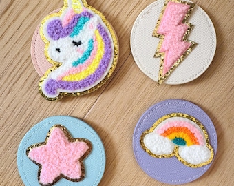 May include: Four round felt patches with different designs. A pink unicorn with a rainbow mane, a pink lightning bolt, a pink star, and a rainbow with clouds.